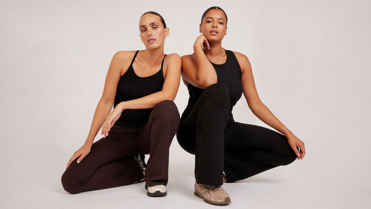 Two women wearing black tops and relaxed pants in neutral colours.