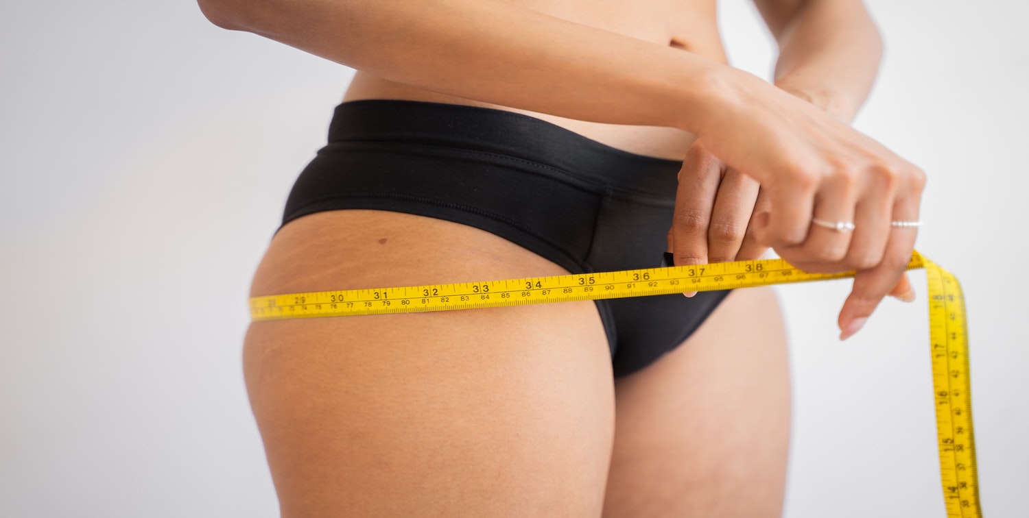 Woman self measuring hips with a tape