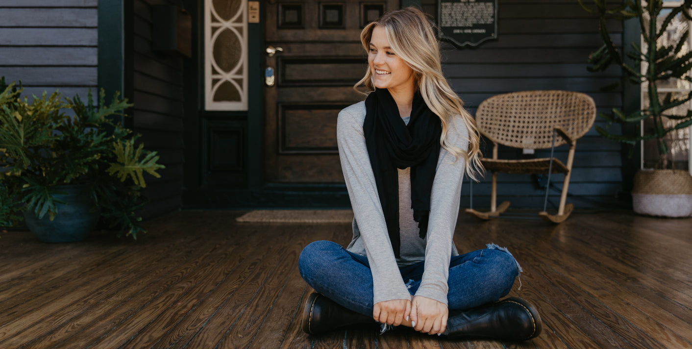 Pretty blonde sitting on a porch dressed in jeans and long sleaved shirt